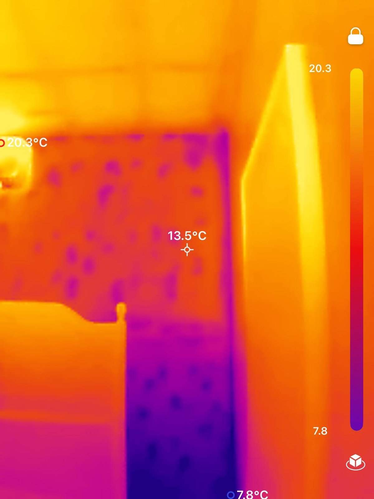 Thermal image of a wall with cool, mottled patches suggesting moisture, beside a warmer doorway or cabinet.