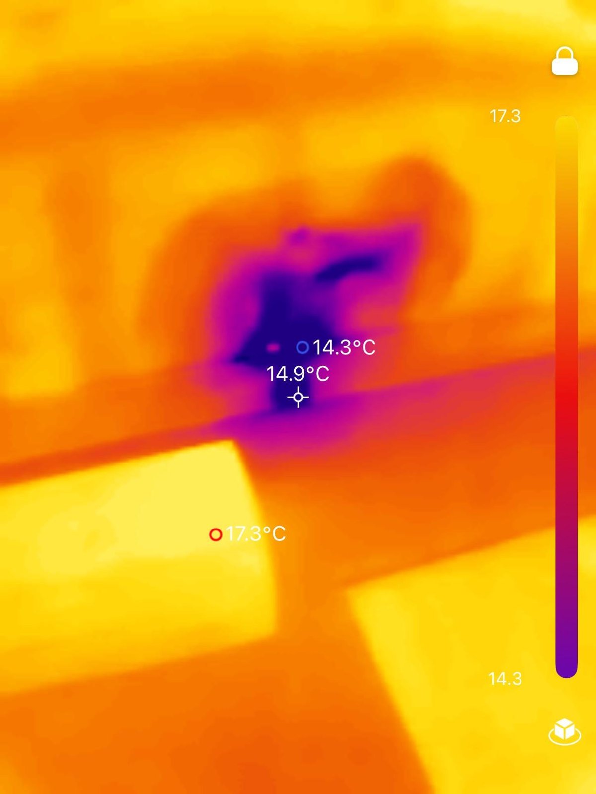 Thermal image showing a cold, moisture-affected patch on a wall or ceiling beside a dark cavity.