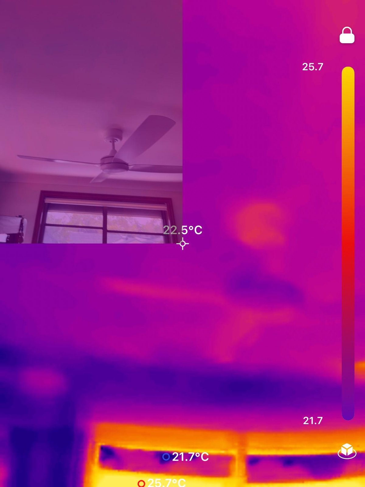 A thermal camera view of a room ceiling, ceiling fan and window, with temperature readings shown on screen.